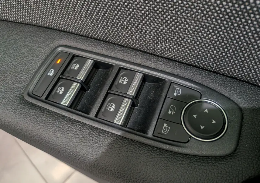 Gros plan sur les commandes des vitres électriques et rétroviseurs du côté gauche d'un Renault Captur 2025 bleu Iron toit noir.