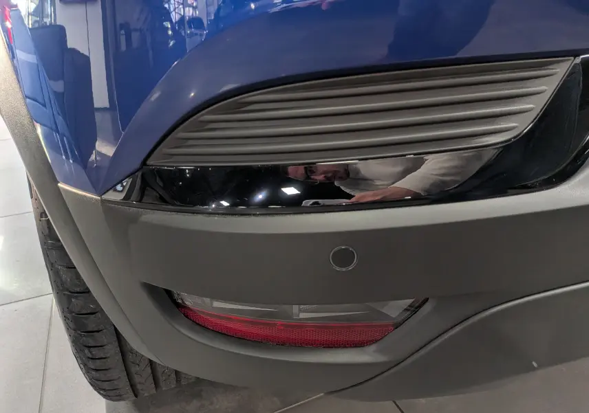 Gros plan sur le pare-chocs arrière droit bleu Iron du Renault Captur 2025 avec feu antibrouillard et capteur de recul.