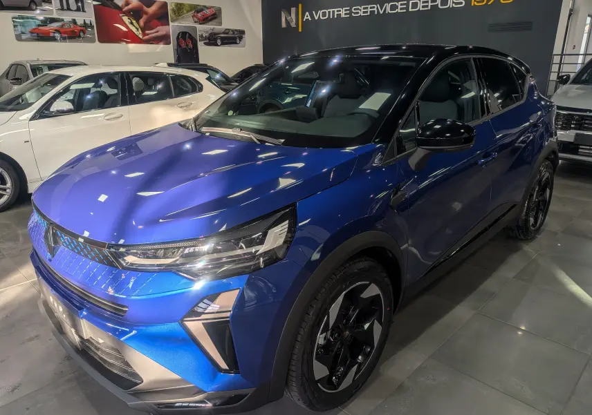 Renault Captur 2025 bleu Iron avec toit noir, vue 3/4 avant droit, jantes noires et éclairage LED moderne.
