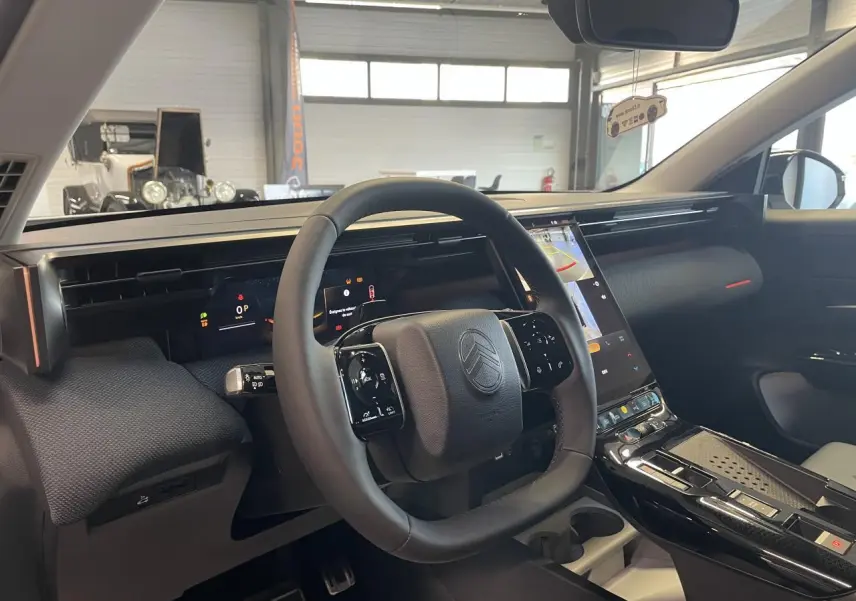 Vue intérieure du tableau de bord et volant noir du Citroën C5 Aircross 2026 avec écran tactile vertical et finitions noires brillantes.