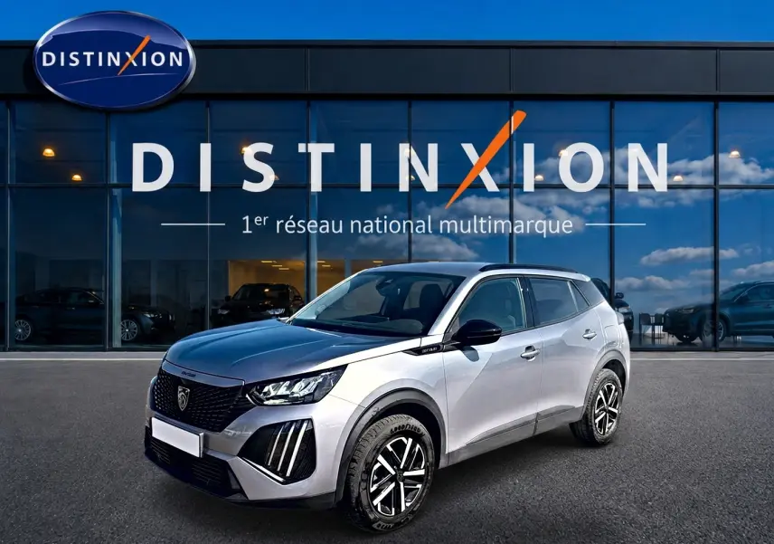 Peugeot 2008 gris 3/4 avant droit, avec calandre noire et jantes distinctives, devant showroom Distinxion.