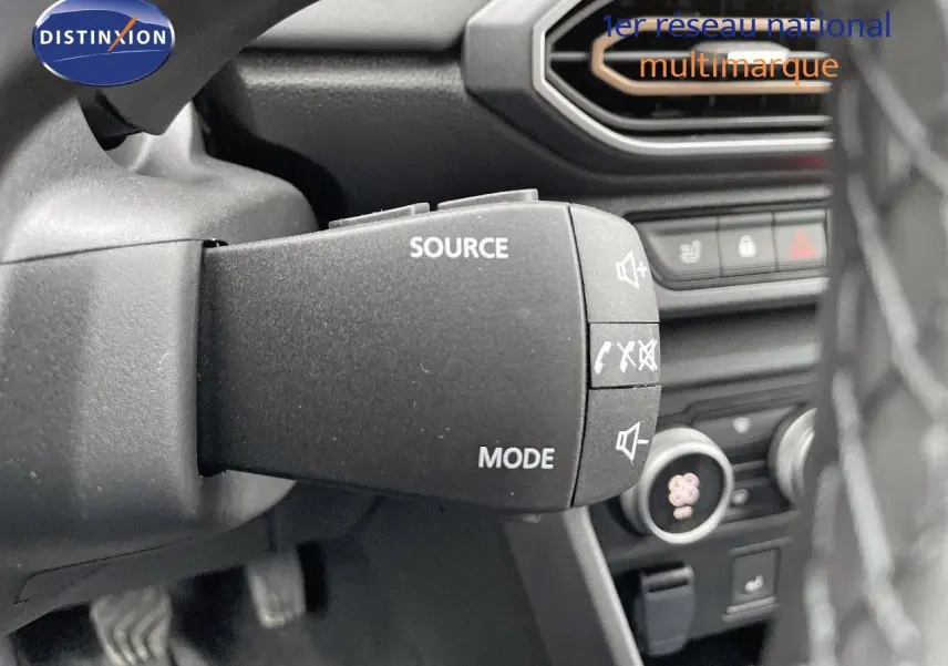 Gros plan sur la commande audio au volant du Dacia Jogger noir nacré, avec tableau de bord en arrière-plan.