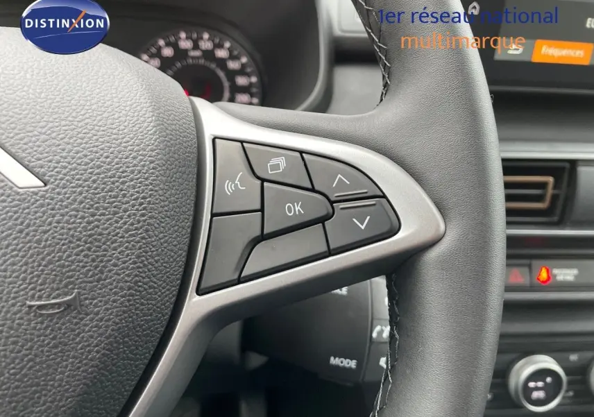 Gros plan sur le volant côté gauche du Dacia Jogger noir nacré, avec commandes multifonctions visibles et tableau de bord flou.