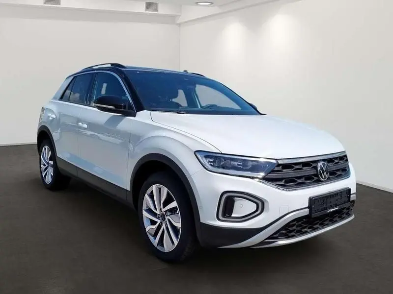 Volkswagen T-Roc blanc pur en 3/4 avant droit avec toit noir et jantes alliage 18 pouces visibles.