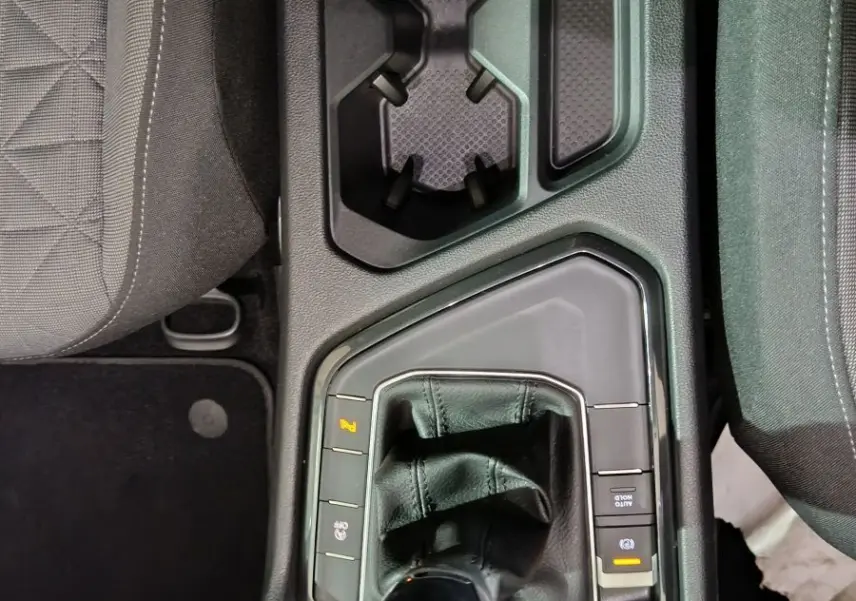 Vue plongeante sur le levier de vitesses manuel et les porte-gobelets du Volkswagen Tiguan bleu, intérieur noir.