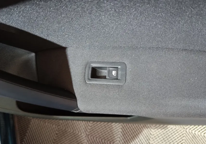 Gros plan sur le bouton de verrouillage des portes sur la garniture intérieure noire d'une Volkswagen Tiguan bleu.