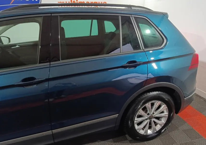 Vue latérale droite d'un Volkswagen Tiguan bleu métallisé, mettant en valeur les jantes alliage et les vitres teintées.
