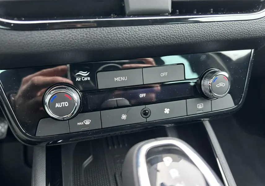 Gros plan sur la console centrale noire du Skoda Kamiq 2025, montrant les commandes de climatisation automatique et le levier de boîte automatique.