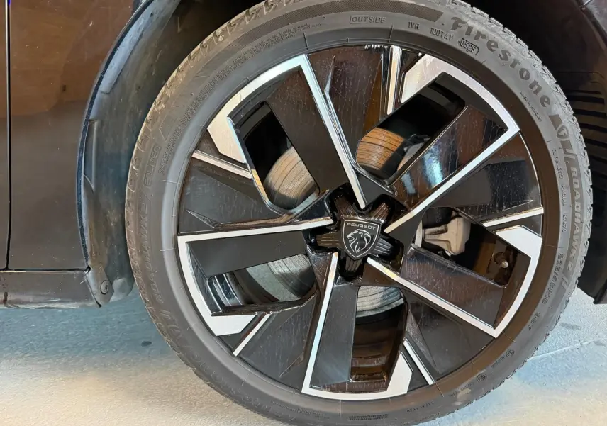 Gros plan sur la jante alliage bi-ton diamantée noire et argentée du côté gauche d'une Peugeot 508 SW noire.