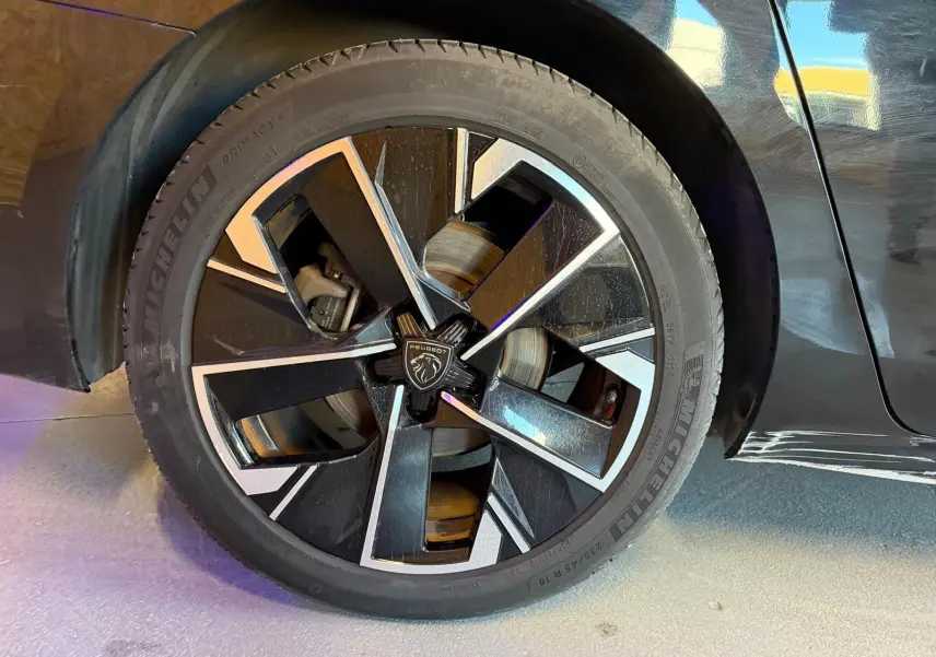 Gros plan sur la jante avant droite noire et argentée diamantée du Peugeot 508 SW noir 2024.