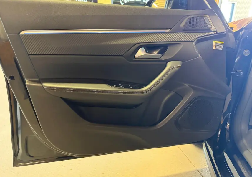 Vue rapprochée de la porte avant gauche noire du Peugeot 508 SW 2024 avec inserts carbone et commandes de lève-vitres.