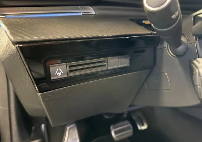 Détail intérieur côté conducteur du tableau de bord noir brillant avec commande d’aide au maintien dans la file Peugeot 508 SW 2024.