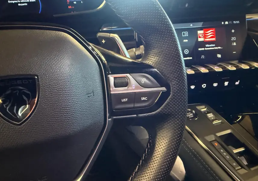 Gros plan sur le volant cuir perforé et la console centrale noire brillante du Peugeot 508 SW 2024, intérieur moderne et high-tech.