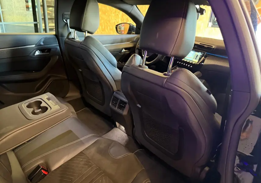 Vue intérieure arrière de la Peugeot 508 SW 2024, sièges en Alcantara noir avec surpiqûres et accoudoir central rabattable.