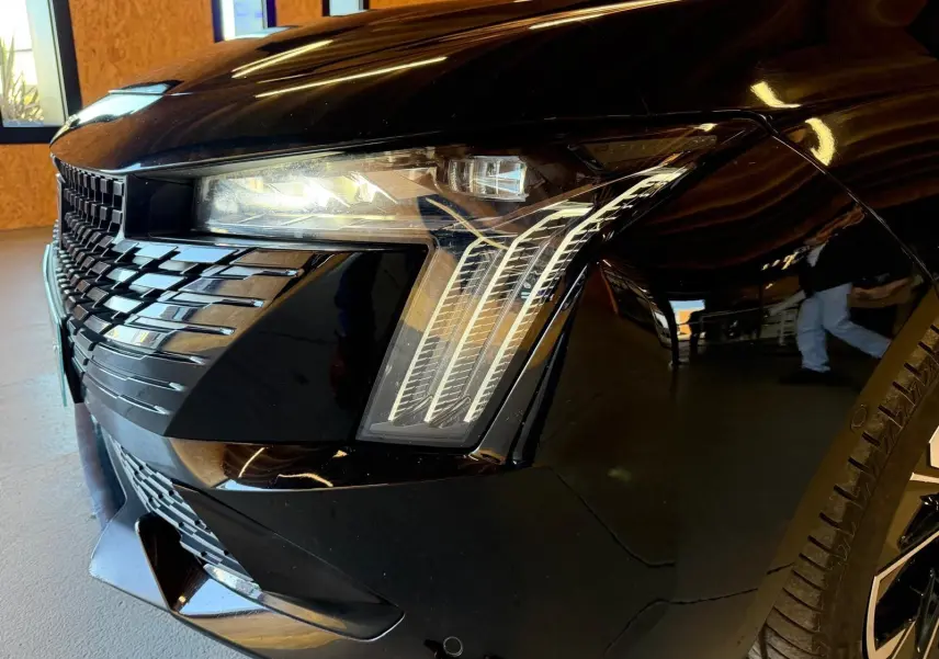 Gros plan sur l'avant droit noir brillant du Peugeot 508 SW 2024, mettant en valeur le phare Matrix LED et la calandre distinctive.