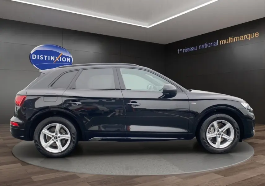 Audi Q5 noir en vue profil côté gauche, avec jantes alliage et badge S Line visible sur l'aile avant.