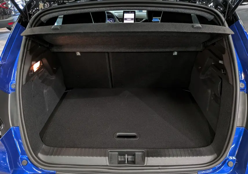 Coffre ouvert vu de l'arrière d'un Renault Captur E-Tech bleu Iron avec toit noir, intérieur de coffre noir et tablette de séparation.