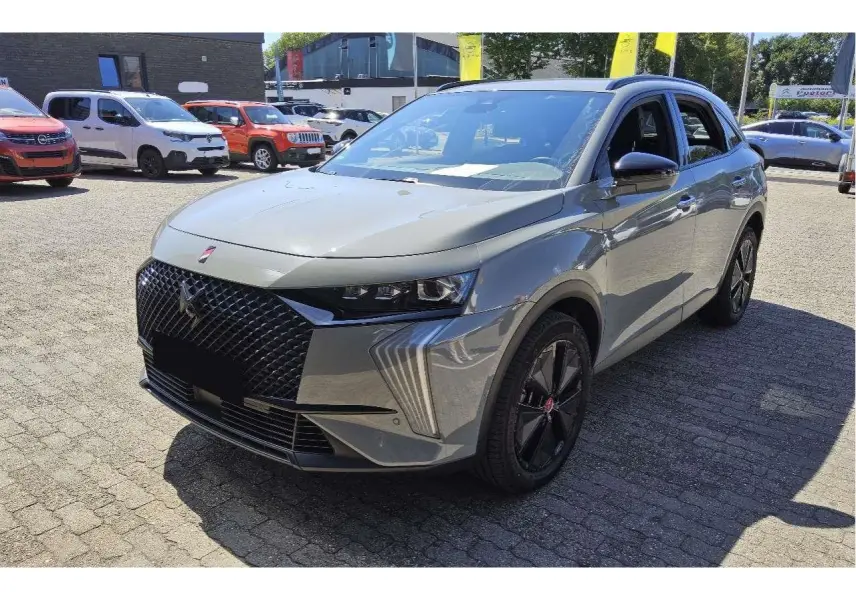 DS7 gris laqué vu en 3/4 avant droit, avec calandre noire texturée et jantes alliage noires distinctives.