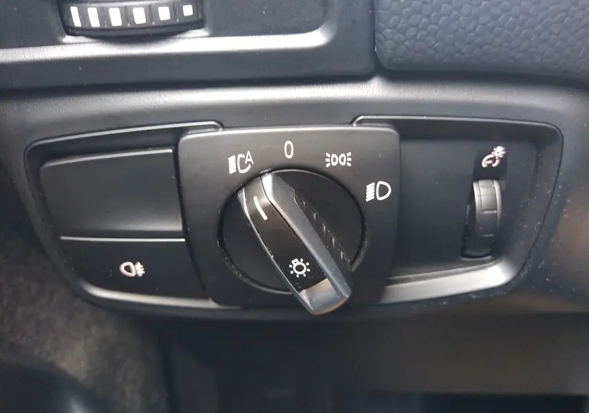 Gros plan sur le bouton de commande des phares du tableau de bord d'une BMW i3 bleu électrique 2022.