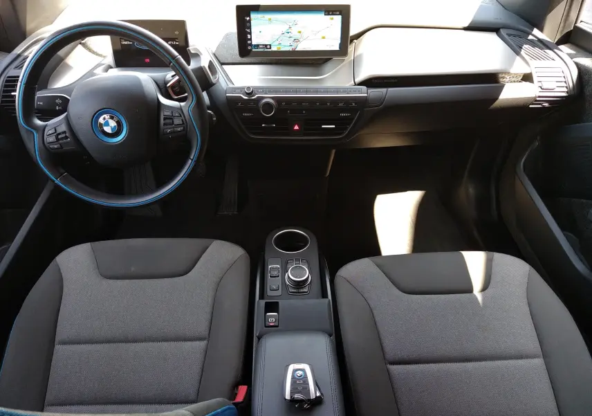 Intérieur de la BMW i3 bleu 2022 en vue plongeante, tableau de bord avec écran GPS et volant au cerclage bleu.