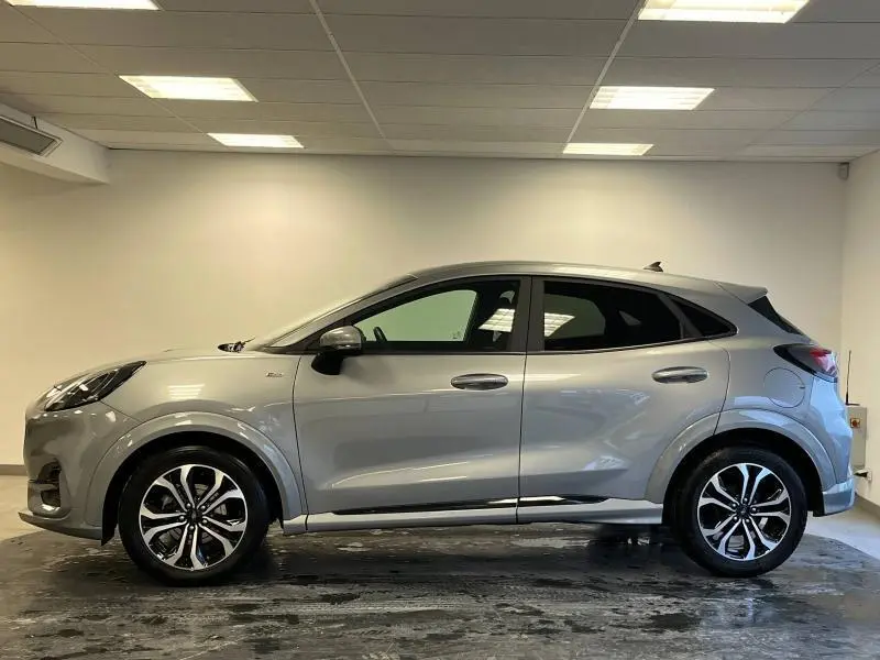 Ford Puma gris Solar métallisé vu de profil côté gauche dans un intérieur neutre avec jantes alliage distinctives.