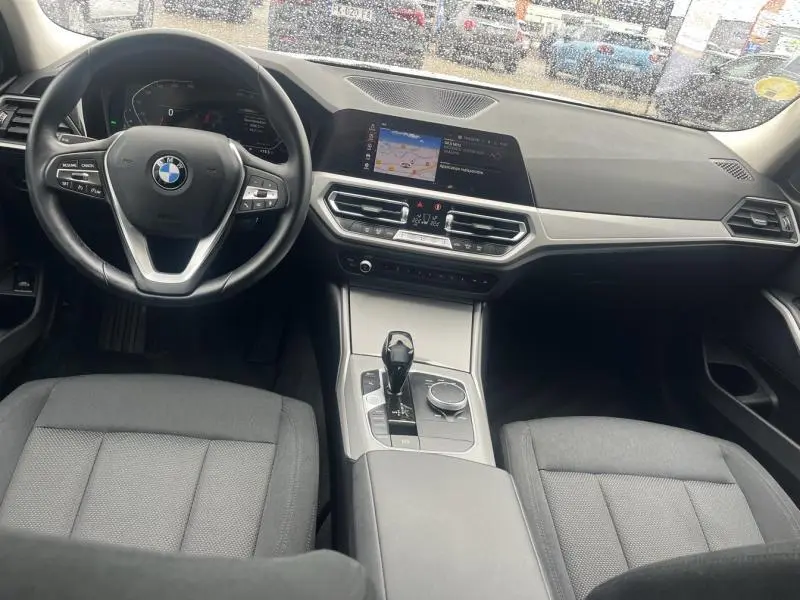 Intérieur BMW Série 3 316dA 2021 vu de face, volant cuir multifonction et écran tactile central allumé.