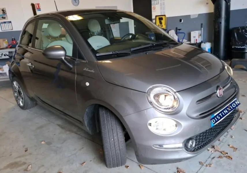 Vue 3/4 avant droit d'une FIAT 500 gris Electroclash avec phares allumés, stationnée en intérieur.