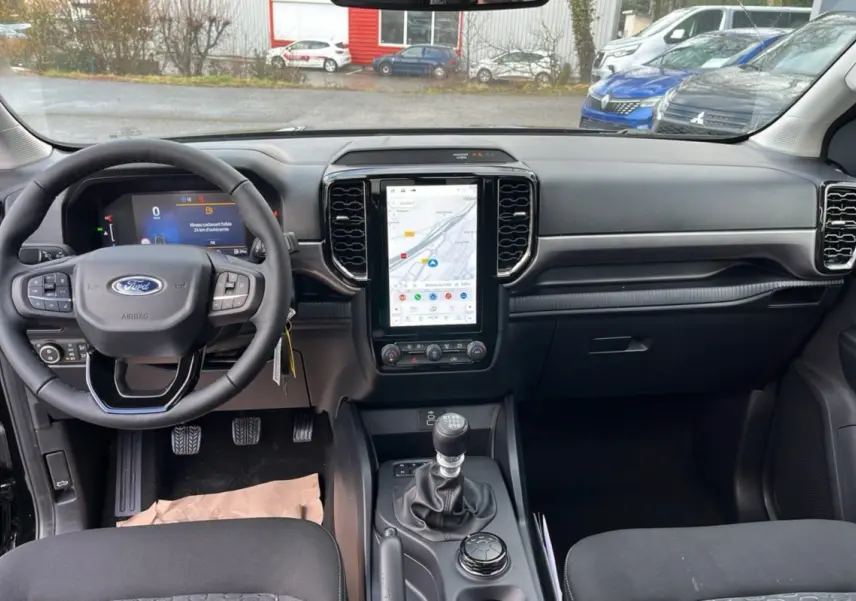 Vue intérieure avant du Ford Ranger noir shadow 2025, avec tableau de bord moderne et écran tactile vertical central.