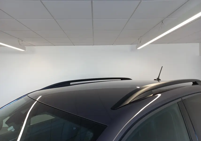 Toit panoramique et barres de toit noires sur Volkswagen T-Cross gris cendré, vue rapprochée en intérieur.