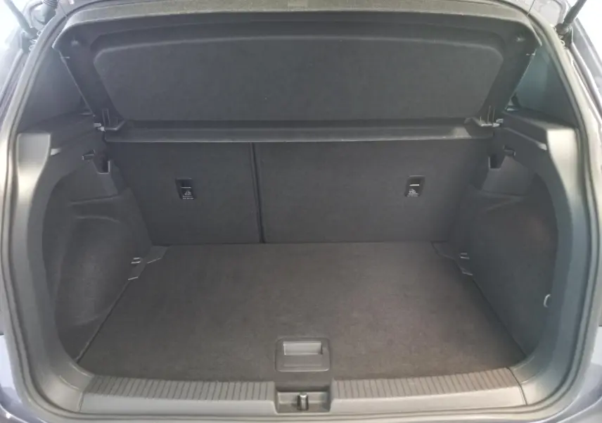 Coffre ouvert du Volkswagen T-Cross gris cendré, vue arrière montrant l'espace de chargement vide et la tablette cache-bagages.