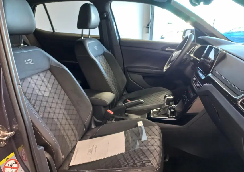 Vue intérieure côté gauche du Volkswagen T-Cross gris cendre, sièges R-Line avec surpiqûres losanges et tableau de bord moderne.