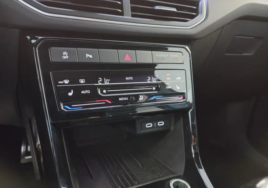 Vue rapprochée de la console centrale du Volkswagen T-Cross 1.0 TSI R-Line, avec commandes climatisation et ports USB visibles.