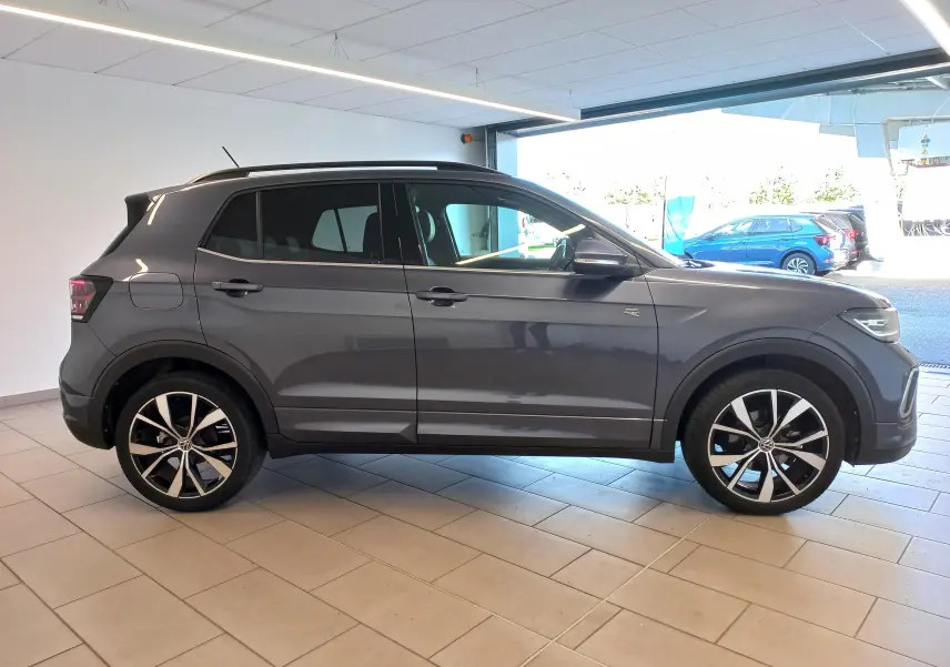 Vue de profil côté gauche d’un Volkswagen T-Cross 2025 gris cendré avec jantes alliage 18 pouces et finition R-Line.