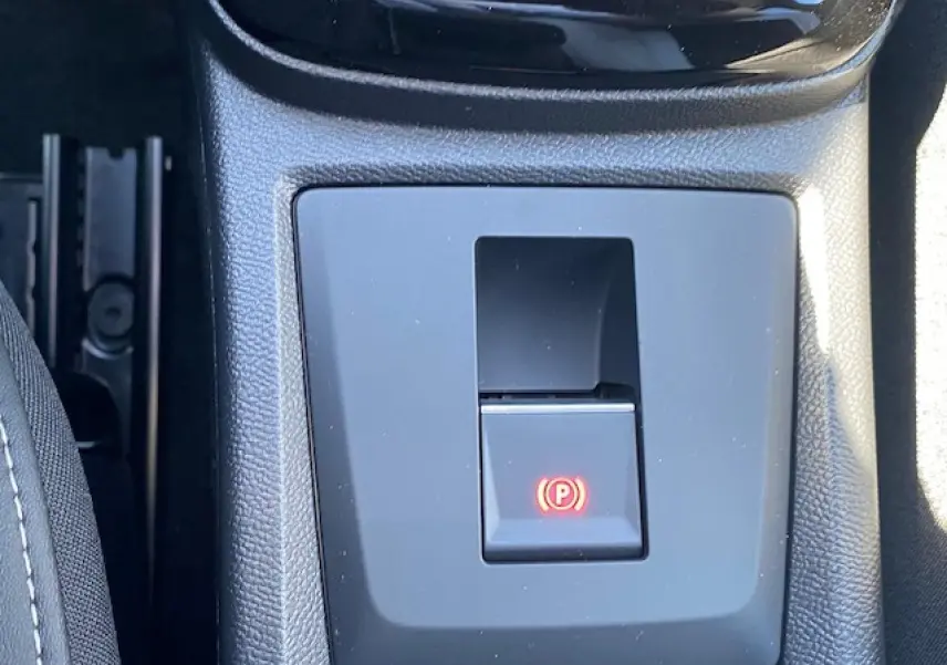 Gros plan sur le frein de stationnement électrique avec témoin rouge dans la console centrale d'une Citroën C3 Aircross gris Mercury.