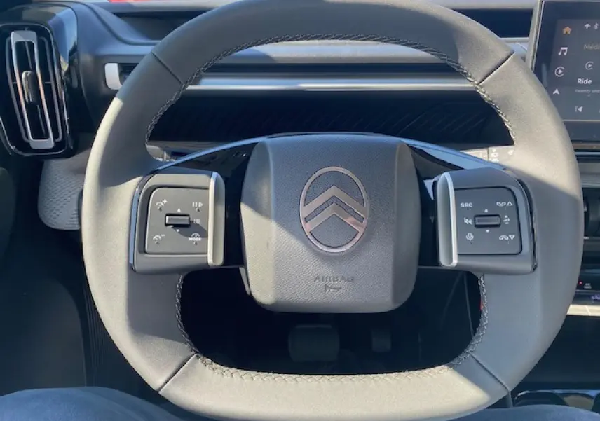 Gros plan sur le volant multifonctions gris du Citroën C3 Aircross 2026 avec commandes intégrées et logo central.