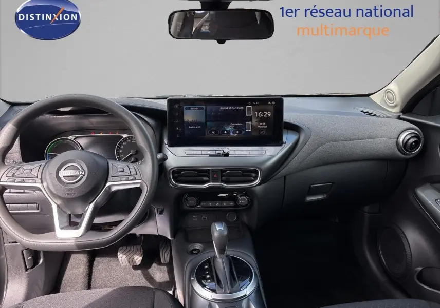 Vue intérieure côté conducteur du Nissan Juke Hybrid 2024, avec tableau de bord moderne et sièges tissu noir.