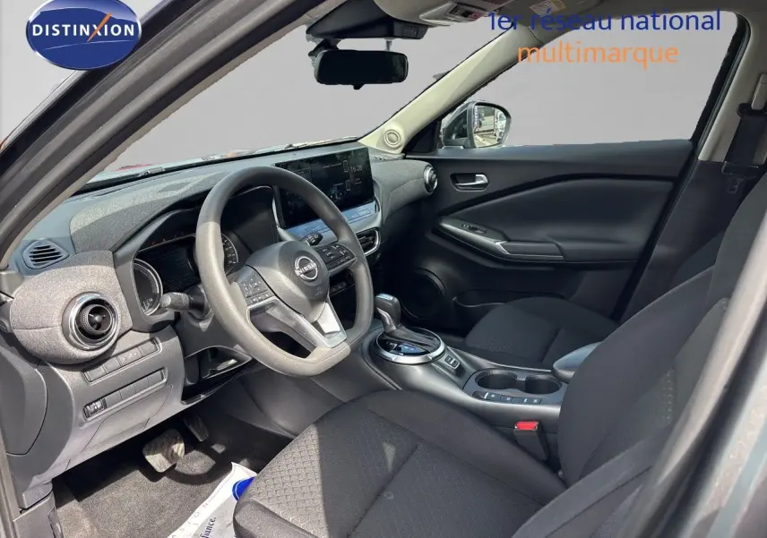Vue intérieure avant du tableau de bord et volant du Nissan Juke Hybrid 2024 avec écran tactile central et finition noire.