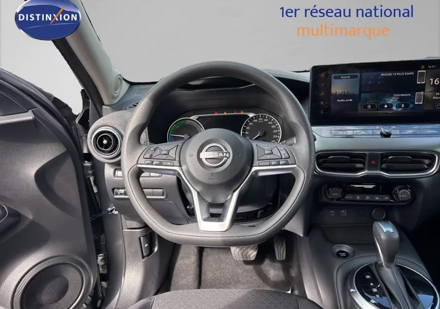 Vue intérieure centrée sur le volant Nissan Juke 2024, tableau de bord moderne avec écran tactile et levier de boîte auto.
