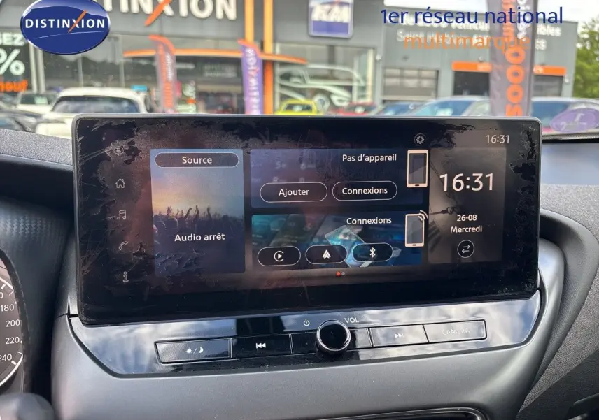 Écran tactile central du Nissan Juke Hybrid 2024 en intérieur, avec commandes audio et caméra visibles.
