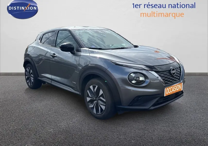 Nissan Juke Hybrid gris squale métal en 3/4 avant droit, avec calandre noire et jantes stylisées.