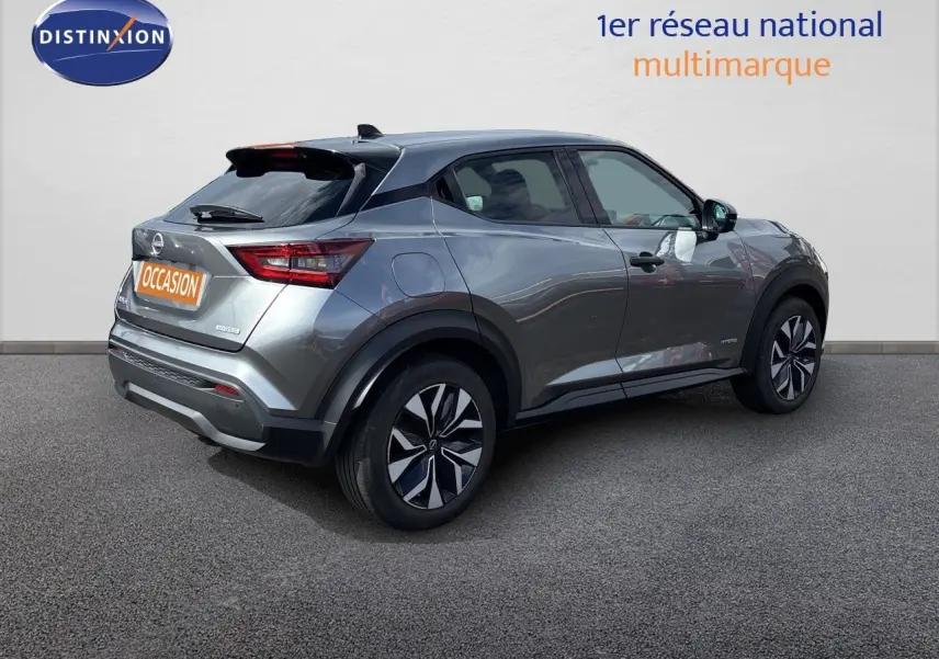 Nissan Juke Hybrid gris squale métal vu en 3/4 arrière droit, avec jantes noires et toit noir contrastant.