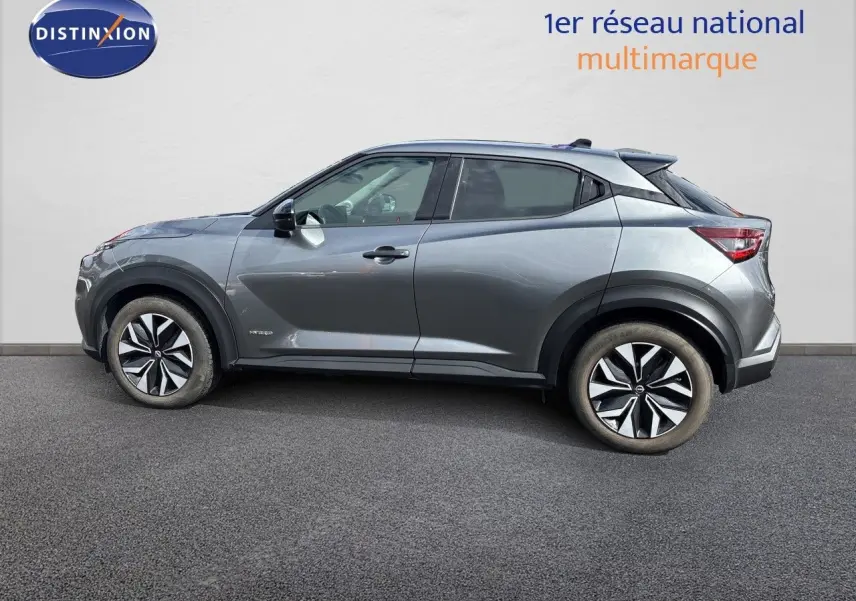 Nissan Juke Hybrid gris squale metal, vue 3/4 arrière droit, avec jantes alliage et vitres teintées.