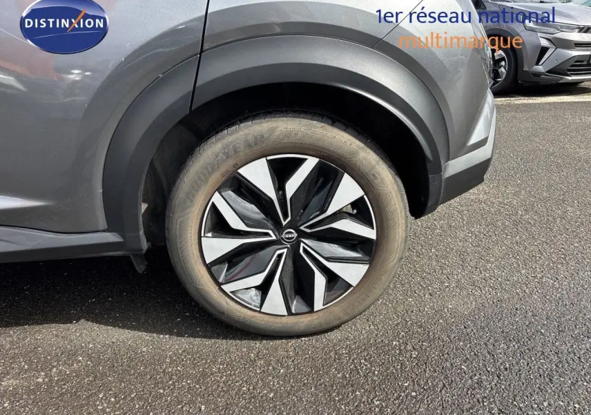 Gros plan sur la roue avant gauche du Nissan Juke gris squale métal, mettant en valeur la jante noire et argentée au design moderne.
