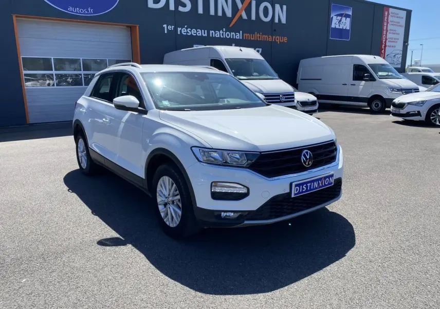 Volkswagen T-Roc blanc pur vu en 3/4 avant droit sur parking devant un bâtiment Distinxion.