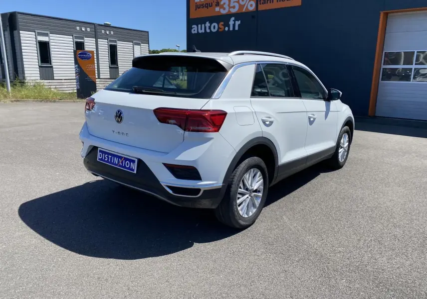 Volkswagen T-Roc blanc pur vu de trois quarts arrière droit sur parking devant bâtiment autos.fr