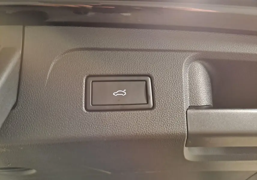 Bouton d'ouverture électrique du coffre sur le panneau intérieur d'un Volkswagen Touran noir Grenadille 2025.