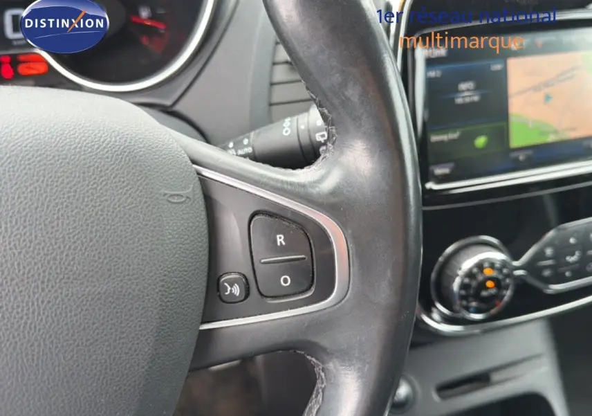 Gros plan sur le volant en cuir noir du Renault Captur 2016 avec commandes intégrées, tableau de bord et écran tactile en arrière-plan.