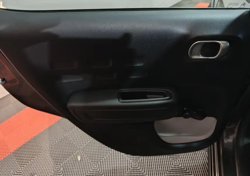 Vue rapprochée de la porte arrière droite gris foncé de la Citroën C3 2024 avec poignée intérieure et manivelle de vitre.