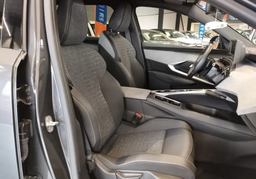 Vue intérieure côté conducteur du Peugeot 5008 2025 gris titanium, sièges tissu et cuir avec console centrale moderne.