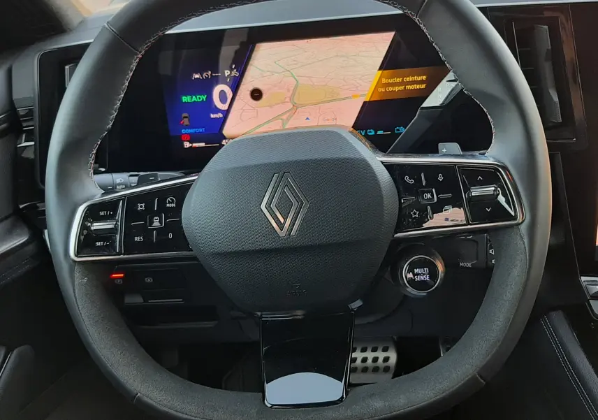 Vue intérieure centrée sur le volant noir du Renault Austral E-Tech 2025 avec écran numérique et commandes intégrées.